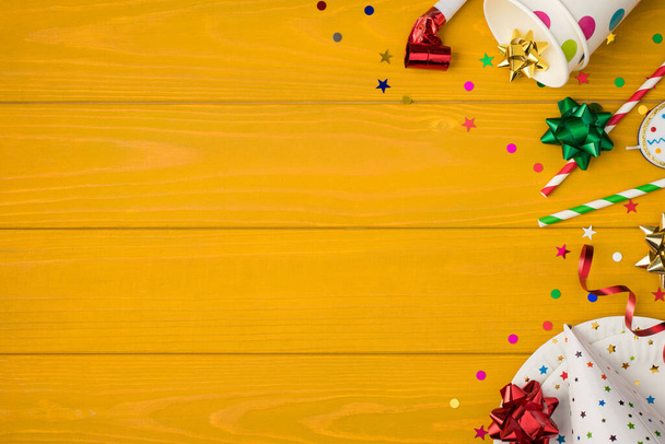 Acima foto de copos beber festa tubules assobiar multicolorido confete arco vela aniversário chapéu e placas isoladas no fundo de madeira amarela com espaço em branco - Foto, Imagem