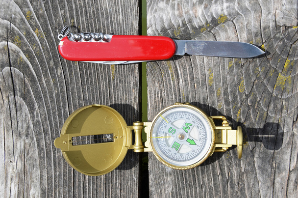Kompassi ja taskuveitsi puupohjalla
  - Valokuva, kuva