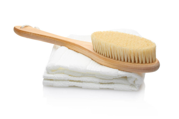 Eine trockene Massagebürste aus natürlichen Materialien und ein Baumwolltuch auf weißem Hintergrund. Sauberkeit und Körperpflegekonzept - Foto, Bild