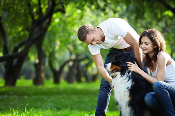 ένα νεαρό ζευγάρι περπατώντας ένα σκύλο στο πάρκο - Φωτογραφία, εικόνα