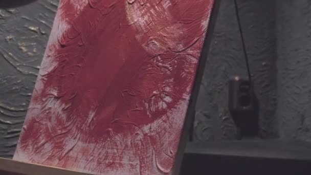Man draws with a brush on a canvas. Abstract painting in pink and gold tones - Footage, Video