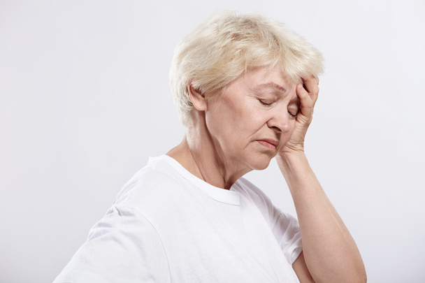 Une femme âgée repose sa tête sur un fond blanc
 - Photo, image