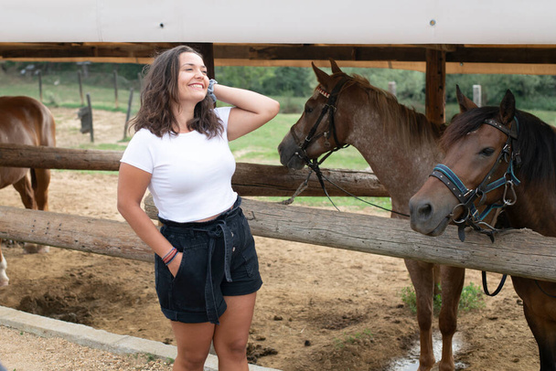 Piękna młoda kobieta ciesząca się na wsi na farmie koni i pozowanie przed kucykiem. Dzień Letni - Zdjęcie, obraz