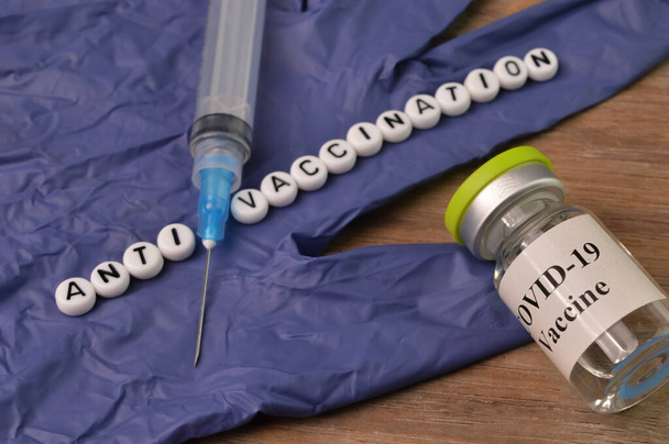 Σύριγγα, γάντι, κομπολόι από εμβόλιο covid-19 και χάντρες αλφάβητο με κείμενο ΑΝΤΙ ΕΜΒΟΛΙΑ - Φωτογραφία, εικόνα