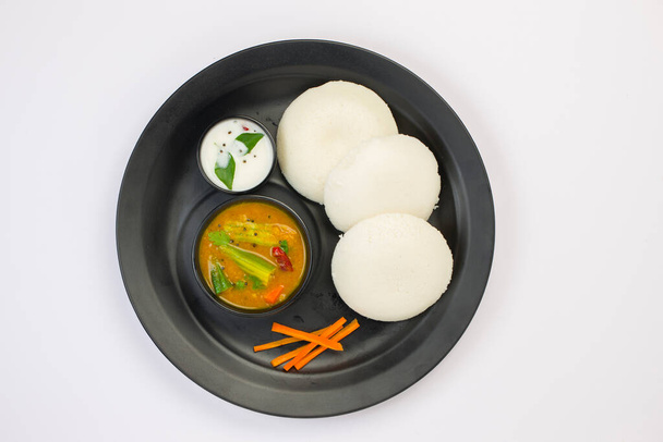 Idly or Idli, south-indian main breakfast item which is beautifully arranged in a black plate on white background. - Фото, изображение