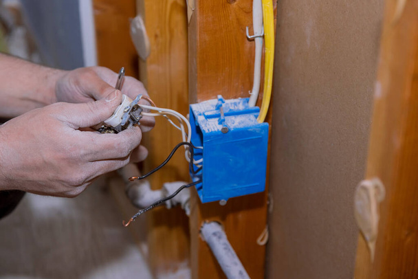 Vervanging van de oude stopcontact door een nieuwe in close-up van de hand van elektricien aan de muur tijdens de sloop - Foto, afbeelding