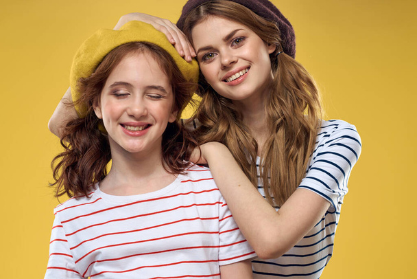 hauska äiti ja tytär yllään hatut muoti hauskaa iloa perheen keltainen tausta - Valokuva, kuva