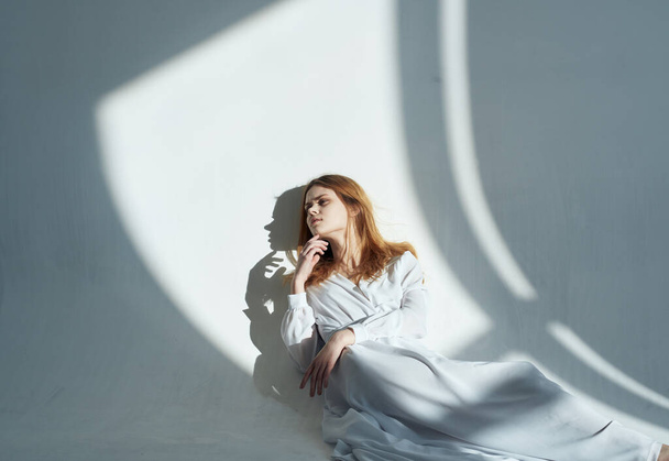 A woman in a dress In a bright room, red hair, a falling shadow - Photo, Image