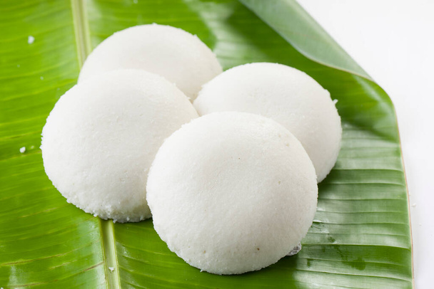 Idly or Idli, south indian main breakfast item which is beautifully arranged in a fresh green banana leaf on white background. - Photo, Image