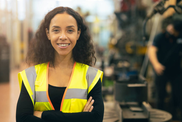 Афроамериканка счастливая работница инженерии рабочей улыбки труд на заводе тяжелой промышленности с хорошей концепцией благосостояния. - Фото, изображение