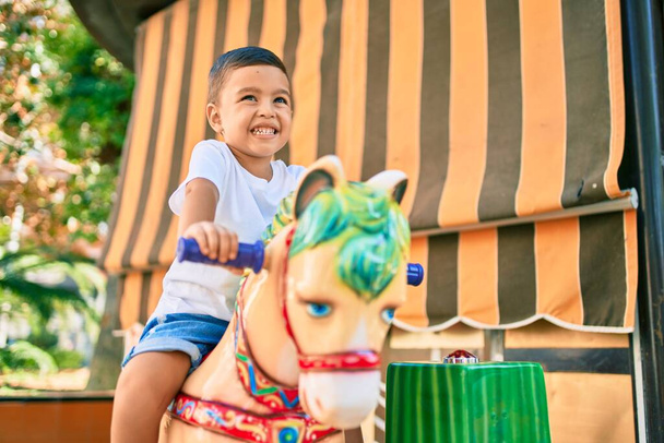 Suloinen latino poika hymyilee onnellinen leikkii puistossa. - Valokuva, kuva