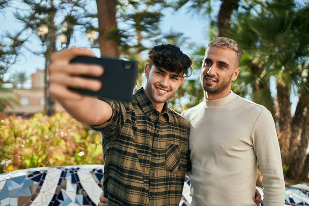Jeune couple gay souriant heureux faire selfie par le smartphone à la ville. - Photo, image