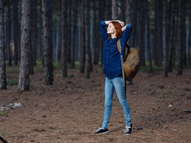 Mujer feliz divirtiéndose en el bosque de pinos con una mochila en la espalda - Foto, Imagen