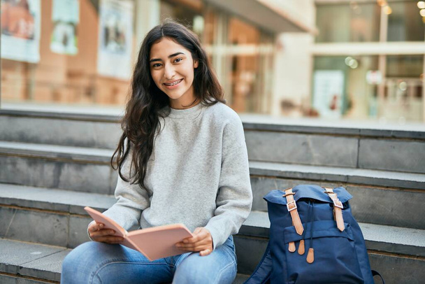 Nuori Lähi-idän opiskelija tyttö hymyilee onnellinen lukeminen kirja yliopistossa. - Valokuva, kuva