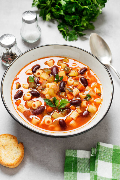Vegetarian minestrone italian soup made with fresh vegetables, pasta and beans. Light gray background. - Photo, Image
