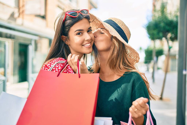 Hermosa madre e hija hispanas sonriendo felices y comprando en la ciudad. - Foto, Imagen