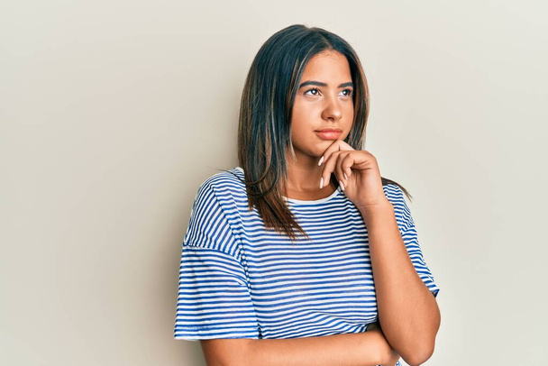 Giovane ragazza latina indossa abiti casual pensando concentrato sul dubbio con il dito sul mento e guardando verso l'alto chiedendo  - Foto, immagini