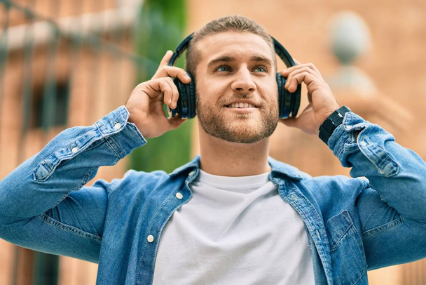 Young caucasian man smiling happy using headphones at the city. - Fotoğraf, Görsel