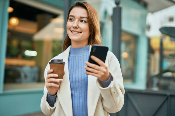 Młoda Latynoska kobieta używająca smartfona i pijąca kawę w mieście. - Zdjęcie, obraz