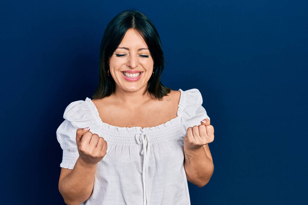 Jeune femme hispanique portant des vêtements décontractés excités pour le succès avec les bras levés et les yeux fermés célébrant la victoire en souriant. concept gagnant.  - Photo, image