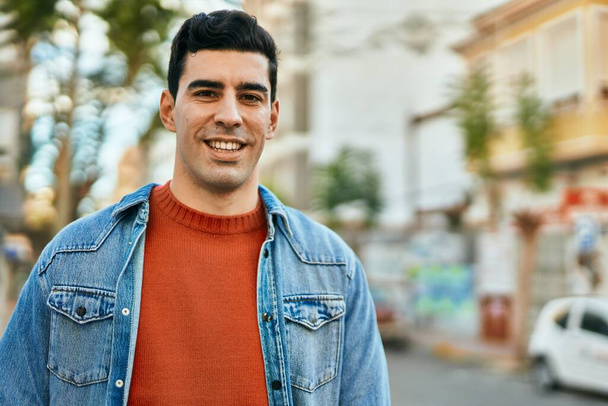 Joven hispano sonriendo feliz de pie en la ciudad. - Foto, Imagen