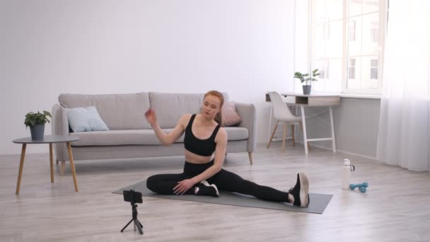 Γυμναστήριο blogger γυναίκα τεντώνοντας και κάνοντας προπόνηση βίντεο στο σπίτι - Πλάνα, βίντεο