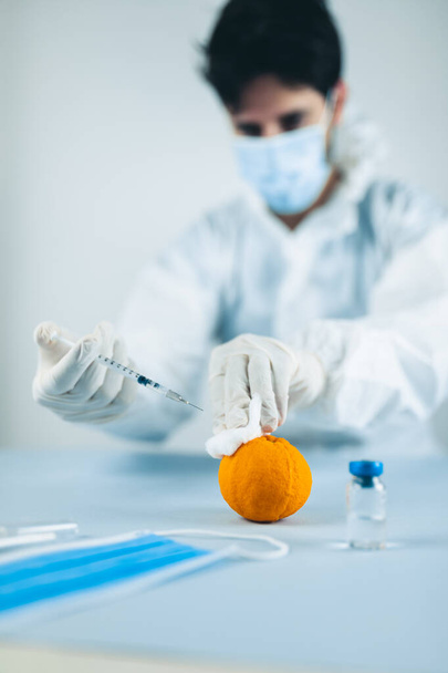 Młody lekarz uczy się robić ukłucia na pomarańczy - Zdjęcie, obraz