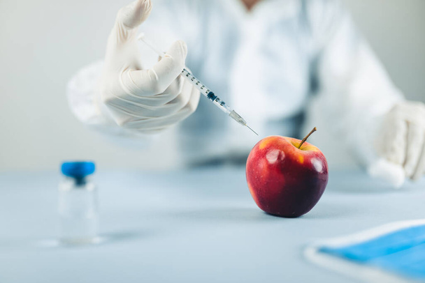 Крупный план молодого врача-мужчины учится делать уколы на яблоке - Фото, изображение