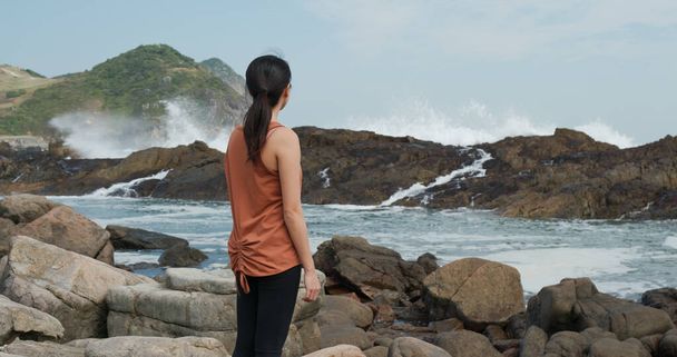 Woman look at the sea wave over the rock - 写真・画像