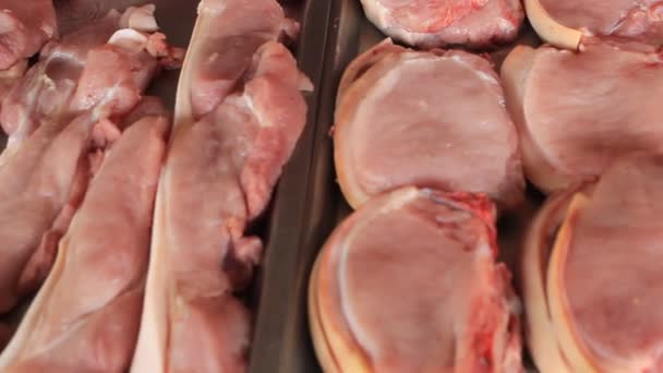 Carne fresca en rodajas de cerdo sin cocer en una venta de exhibición de mercado fresco - Imágenes, Vídeo