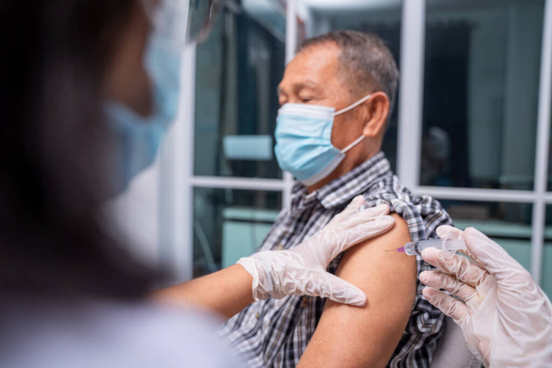 Médico haciendo una vacunación en el hombro del paciente de edad avanzada, inyección de vacuna contra la gripe en el brazo, coronavirus, enfermedad de la vacuna covid-19 preparándose para la vacuna de ensayos clínicos en humanos. - Foto, imagen