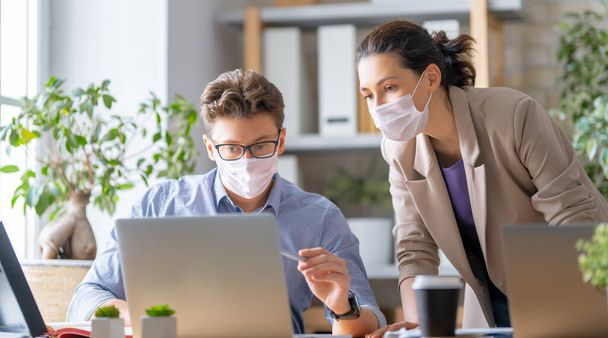 Businessman and businesswoman with medical mask working in office. Covid-19 time. - Foto, Imagen