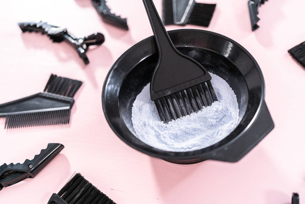Hair color dye powder in a black plastic mixing bowl on a pink background. - Photo, Image