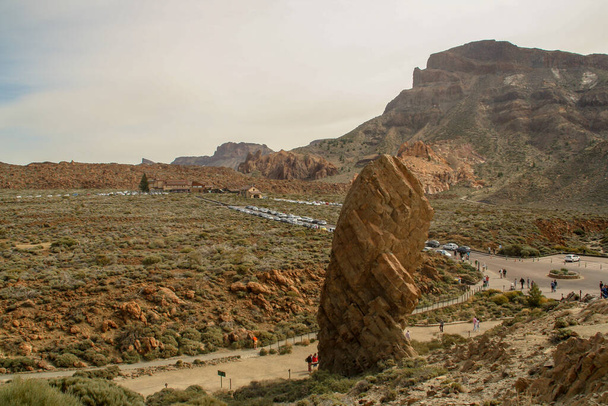 The boulder named Cinchado in the volcanic landscape of the Teide volcano. Tourists visiting the Teide Volcano and the hotel Las canadas del Teide at the background. Tenerife Island, Spain. - 写真・画像