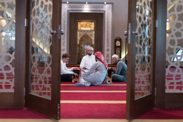 Grupo de muçulmanos lendo, recitando e lembrando o Alcorão durante o ramadãodentro da mesquita moderna e nova - Foto, Imagem