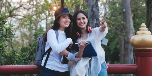 Üniversiteden iki genç öğrenci parkta gezintiden zevk alıyor ve ilginç bir şey gösteriyorlar. Eğitim, eğitim, üniversite, üniversite, mezuniyet konsepti. - Fotoğraf, Görsel