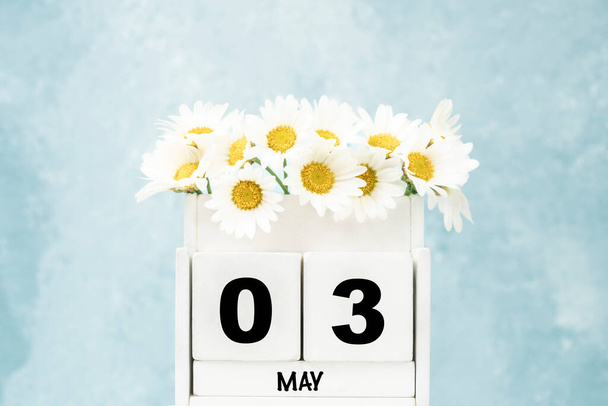 Λευκό ημερολόγιο κύβου για το Μάιο με λουλούδια μαργαρίτα πάνω από μπλε φόντο με χώρο αντίγραφο - Φωτογραφία, εικόνα