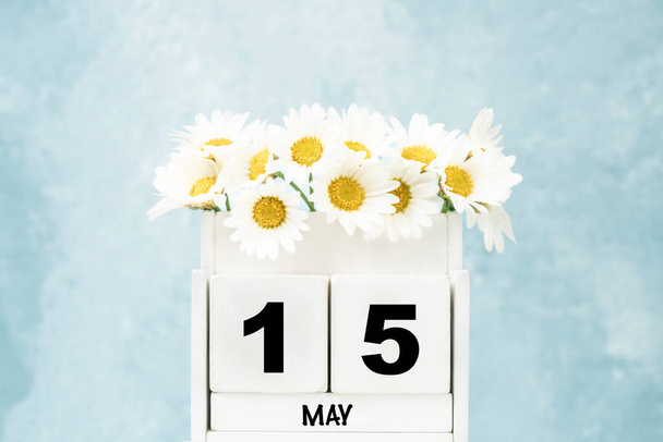 Λευκό ημερολόγιο κύβου για το Μάιο με λουλούδια μαργαρίτα πάνω από μπλε φόντο με χώρο αντίγραφο - Φωτογραφία, εικόνα