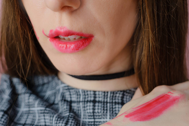 hermosa modelo joven con lápiz labial rosa untado en su mano. Foto de alta calidad - Foto, Imagen