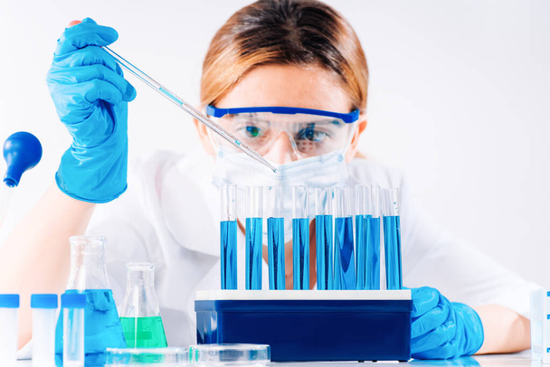 Female Research Scientist maakt gebruik van Micropipette Filling Test Tubes. Een laboratoriumassistent in een laboratorium met reageerbuizen produceert vaccinmonsters. Ontwikkeling in een laboratorium van vaccins, medicijnen. - Foto, afbeelding