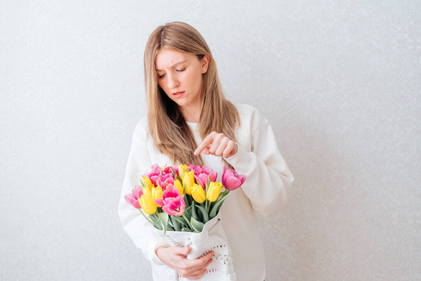 Грустная женщина держит тюльпаны. - Фото, изображение