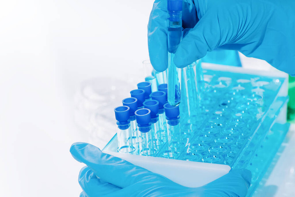 Γυναίκα Επιστήμονας Έρευνας Χρησιμοποιεί Σωλήνες Δοκιμών Συμπλήρωσης Μικροπιπέτων.Ένας εργαστηριακός βοηθός σε ένα εργαστήριο με δοκιμαστικούς σωλήνες παράγει δείγματα εμβολίων. Ανάπτυξη εργαστηρίου εμβολίων, φαρμάκων. - Φωτογραφία, εικόνα