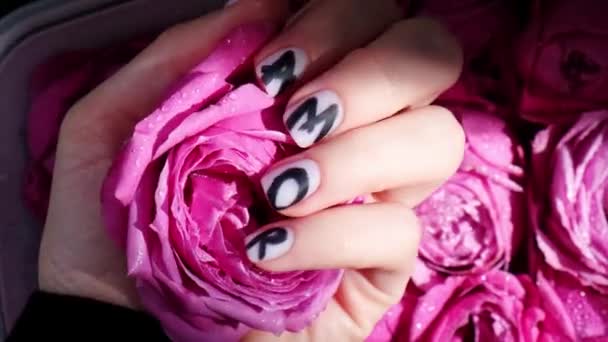 AMOR word on nails manicure hold Pink rose flower on black silk fabric. Minimal flat lay nature. Female hand. Love - Footage, Video