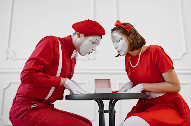 Male and female mime artists are looking on gift. Pantomime theater, parody comedian, positive emotion, humour performance, funny face mimic and grimace - Photo, Image