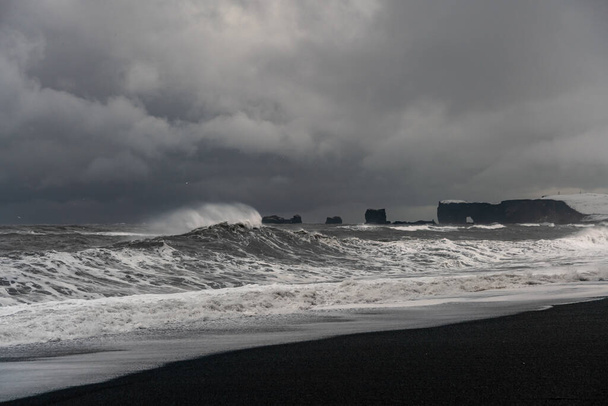 Штормовые волны на черном вулканическом пляже возле знаменитых скал Рейнисфьяра на южном побережье Исландии - Фото, изображение