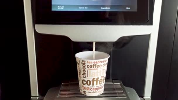 Una cafetera espresso profesional vertiendo leche con leche capuchino en una taza de papel con algunos tipos de textos relacionados con bebidas. - Metraje, vídeo