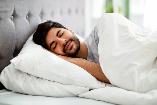 Descansando. Hombre árabe dormido descansando pacíficamente en su cómoda cama en casa, teniendo buenos sueños - Foto, Imagen