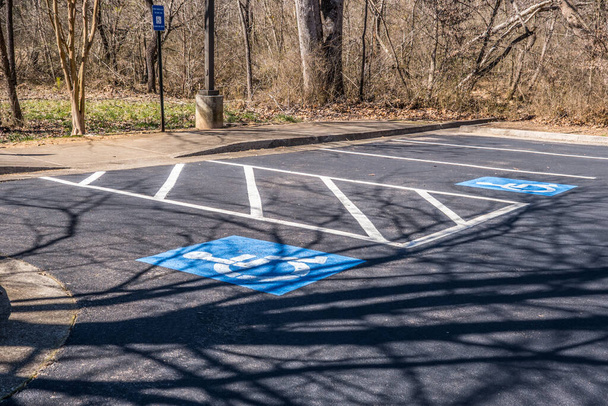 Plazas de aparcamiento reservadas para discapacitados estacionamiento solo con señalización que indica la ley con símbolos de silla de ruedas azules pintados en el asfalto en un parque en un día soleado en invierno - Foto, imagen