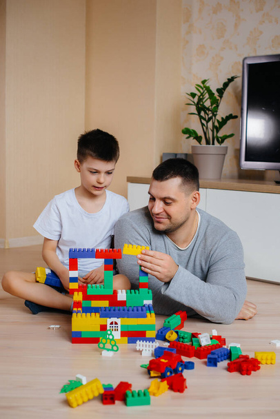 A little boy together with his father is played by a constructor and builds a house. Construction of a family home. - Foto, afbeelding