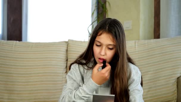 mooi tiener meisje schilderen haar lippen in haar woonkamer - Video